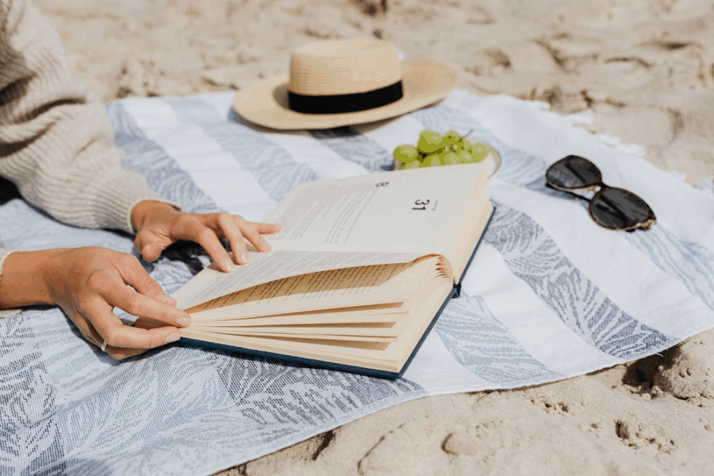 Person enjoying one of the best beach reads in 2025 while relaxing on the sand.