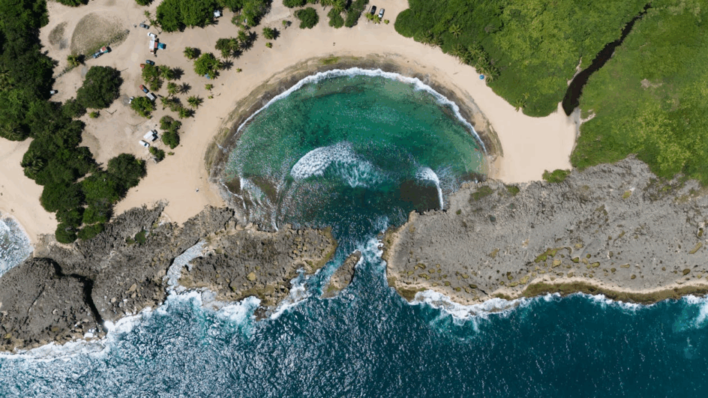 Aerial view of a hidden Caribbean beach surrounded by rocky cliffs and turquoise water