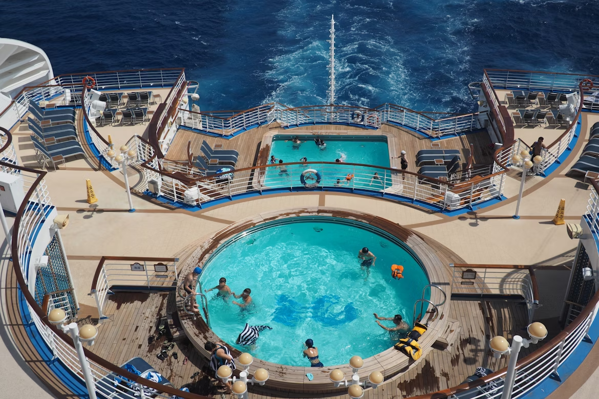 Aerial view of a family-friendly cruise ship deck with swimming pools and ocean views