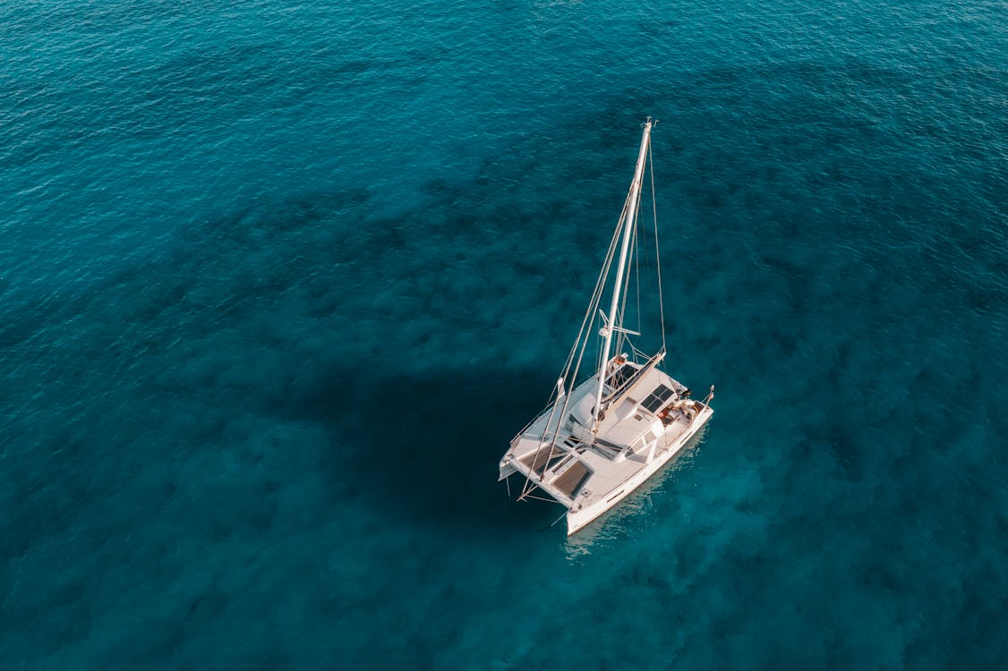 Aerial view of a private yacht charter sailing through crystal-clear turquoise waters