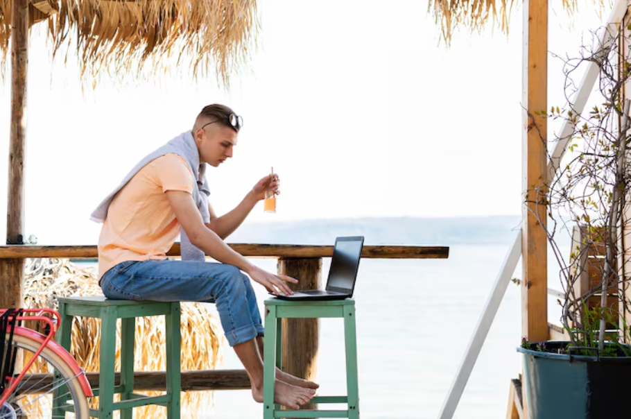 Man working remotely on a laptop at a tropical beach, representing the digital nomad lifestyle