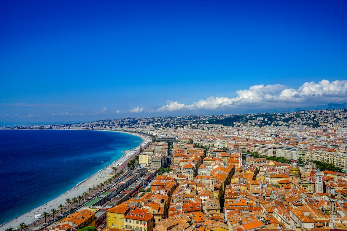 Aerial view of Nice, France, showing the Promenade des Anglais, turquoise coastline, and terracotta rooftops along the French Riviera.