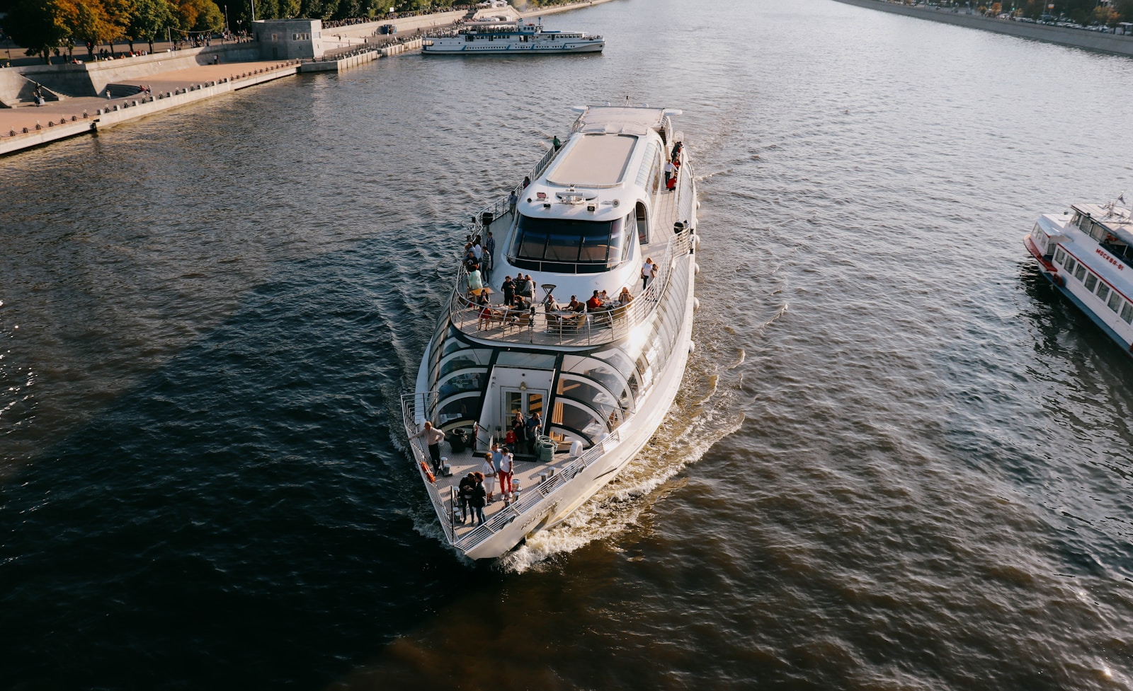 a white boat traveling down a river next to a bridge